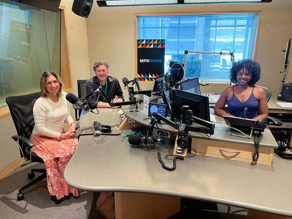 three people smiling in a broadcast studio
