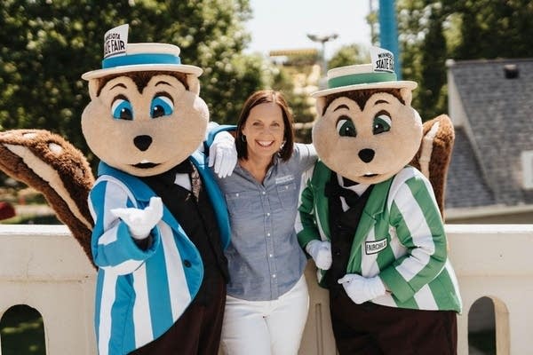 A woman poses with two costumed mascots