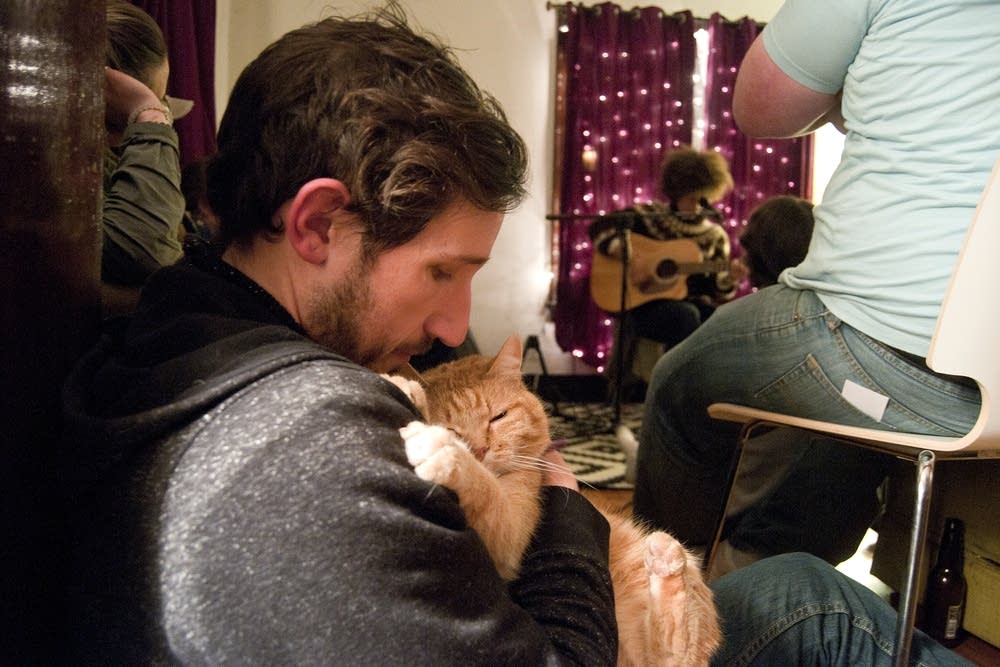 Host Colin Scharf holds his cat during a concert.
