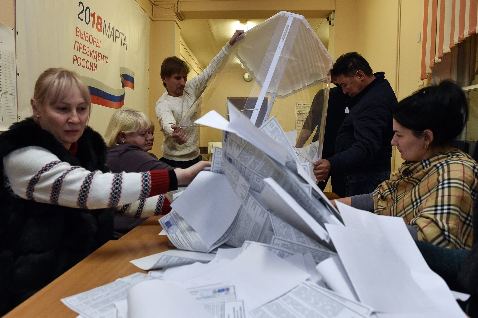 Workers empty a ballot box for counting during Russia's election.