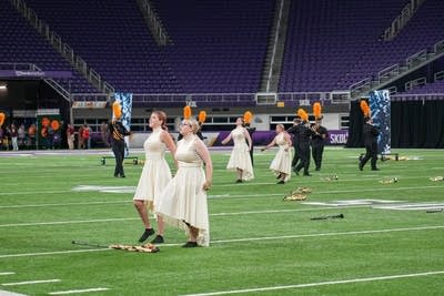 A marching band performs on the field of a football stadium.