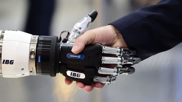 A person shakes hand with a robot at the booth of IBG Automation during the Hanover Fair ('Hannover Messe') on April 23, 2018 in Hanover, northern Germany. - The Hanover technology fair runs until April 28, 2018, with Mexico as partner country.
