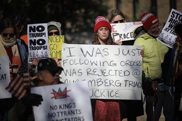 A sign held by a woman reads "'I was just following orders' was rejected at nuremberg trials."