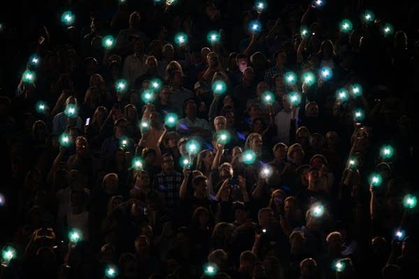 Music fans hold up their phones in a stadium