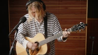 A musician plays guitar in a recording studio