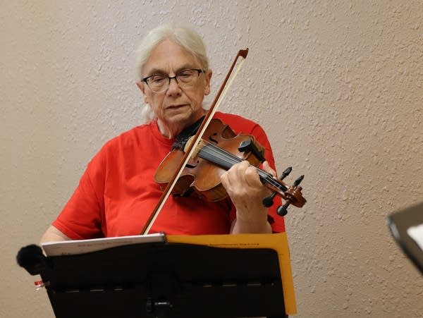 a woman in a red shirt plays a violin