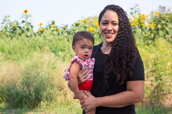 A woman stands outside with a baby.