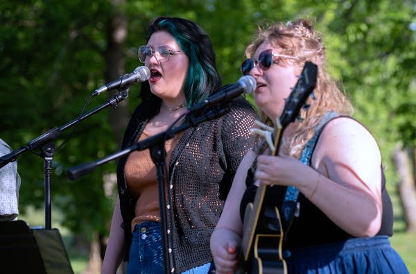 Two people outside singing into mic