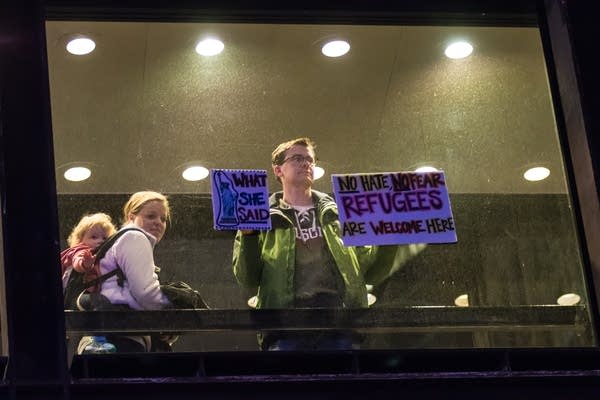 A man in a skyway holds up signs in support of protesters