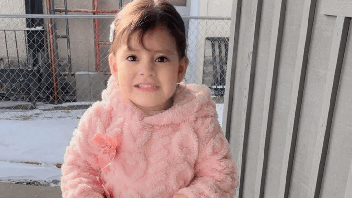 A girl in pink smiles for a photo