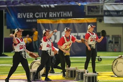 A marching band performs on the field of a football stadium.