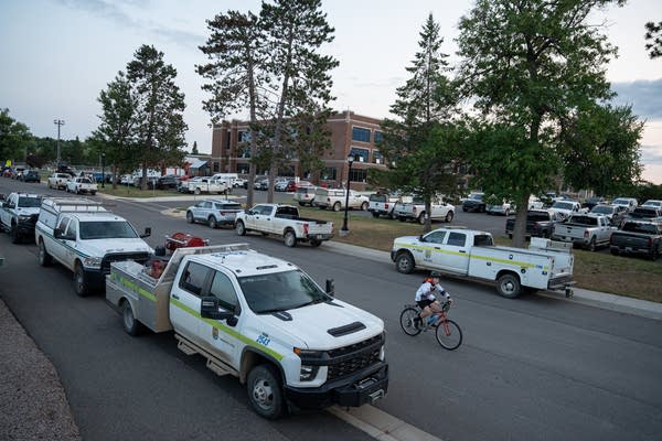 A street next to a school is packed with fire response trucks.