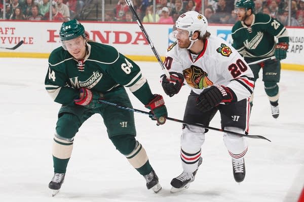 Brandon Saad #20 of the Chicago Blackhawks is defended by Mikael Granlund #64 of the Minnesota Wild in Game Three of the Western Conference Semifinals during the 2015 NHL Stanley Cup Playoffs on May 5, 2015 at the Xcel Energy Center in St. Paul, Minnesota.