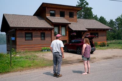 a man and a woman standing outside of their house