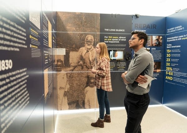 Two people read panels at an exhibit