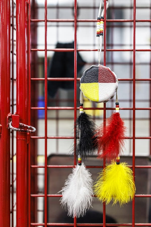 A red, white, black and yellow medicine wheel decoration hangs from a red equipment cage.