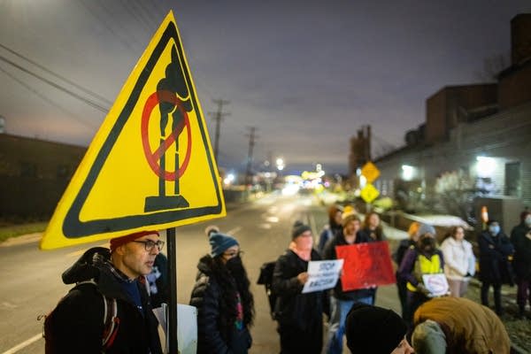 A person holds a large yellow sign at aprotest