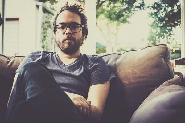 A man sits on a sofa near a window