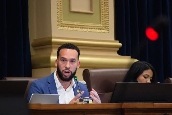 A council member speaks into a microphone during a meeting.