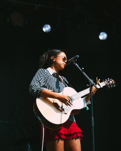 Jensen McRae performing on stage with an acoustic guitar