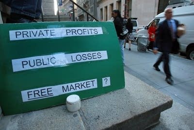 A sign questions the market system on Wall St.