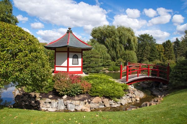 A Japanese garden with a small bridge and tower among greenery.