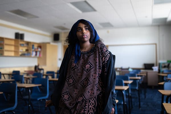A student wearing a headscarf poses for a portrait