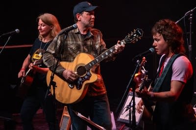 Three musicians perform onstage.