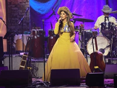 A woman in an elegant dress sings onstage
