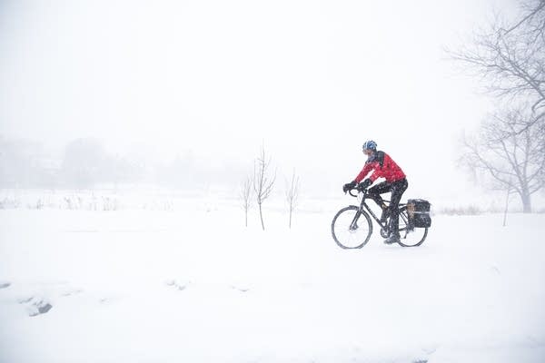 A person bikes through heavy snow around Lake of the Isles in Minneapolis on Monday, March 5, 2018.