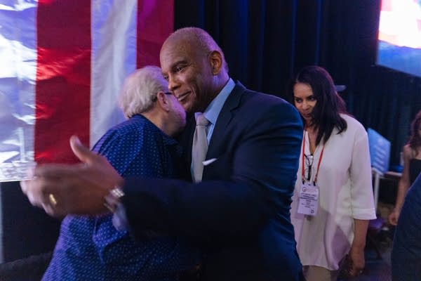 Two men lean in for a hug.