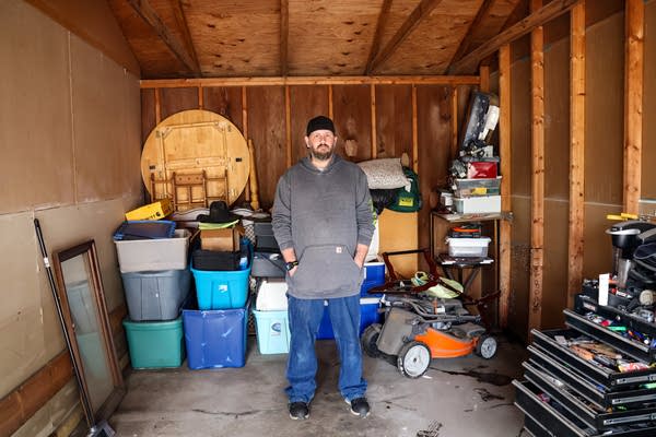 A man poses for a photo in the middle of his garage.