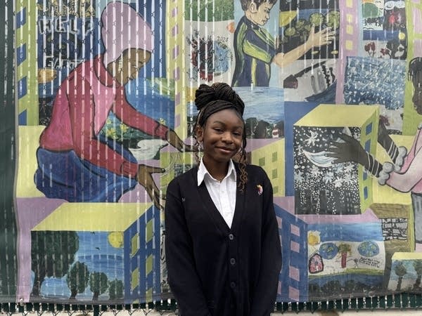 Former elementary student Virtue Onoja stands in front of part of the mural she helped paint. 