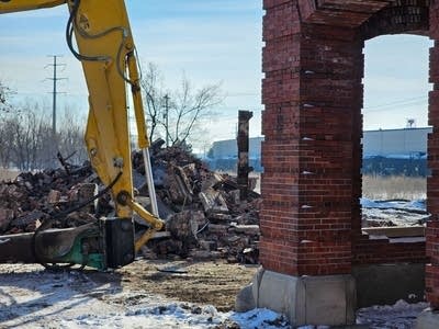 a crane picks up bricks from a demolished structure