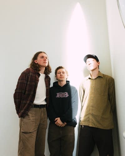 Three guys stand in a beam of light together for a portrait