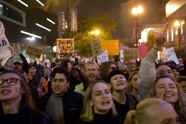 A crowd chant and hold signs