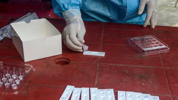 A health official checks nasal and throat swab samples for COVID-19. Testing and rapid results are essential in controlling the disease.