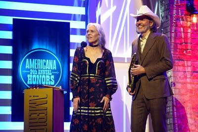 Two people speak onstage after winning an award