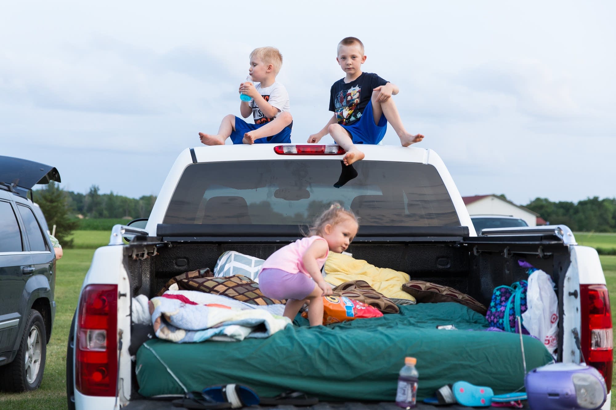 Siblings play on the back of their family's pick-up truck.