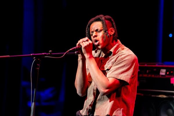 Man singing into microphone with eyes closed