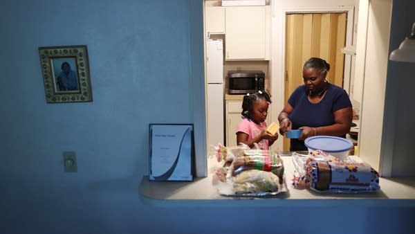 A woman makes grilled cheese with her granddaughter after being laid off from her job early in the pandemic.