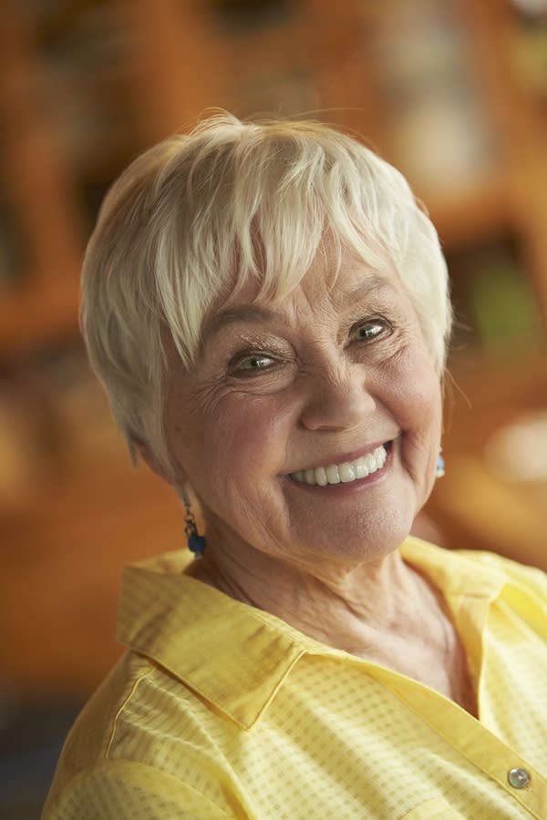 A woman in a yellow shirt smiles for photo