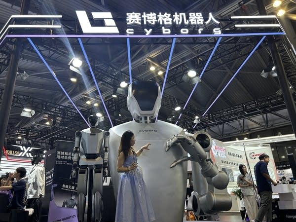 Shanghai AI conference young woman forming the shape of a heart with a humanoid robot