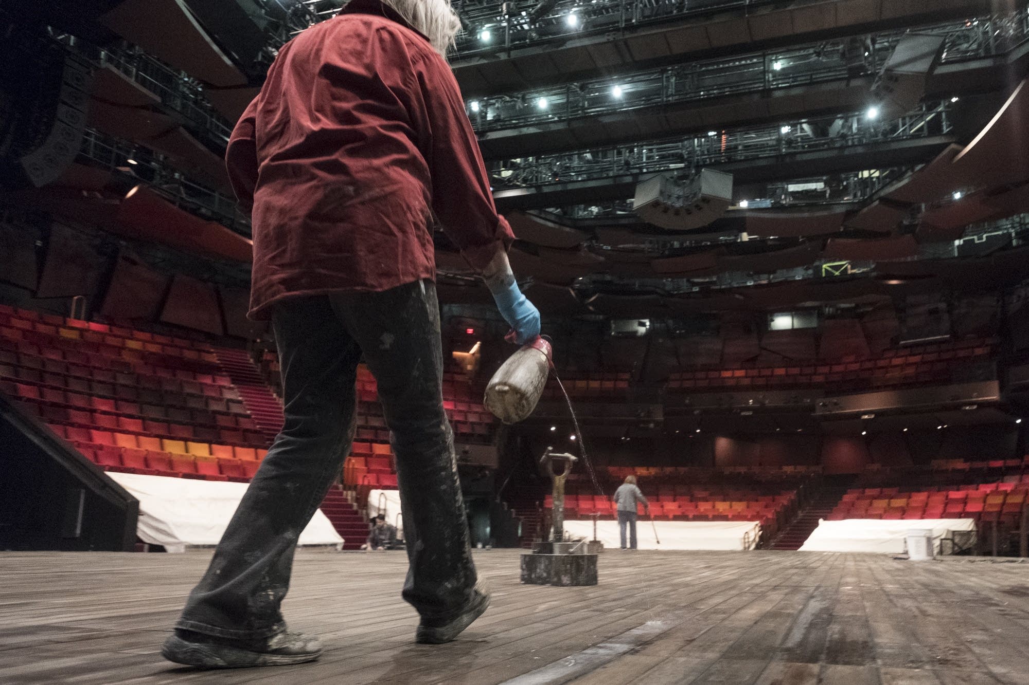 Rebecca Pavlenko paints the wooden floor of a stage.