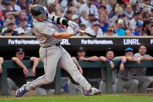 A Colorado Rockies baseball player makes contact with the ball while at bat.