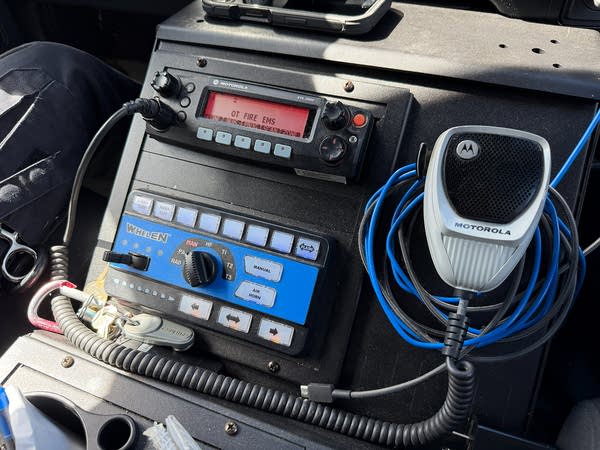 A handset and radio are seen on the dashboard of a vehicle.