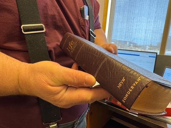 A man holds a leather bound bible.