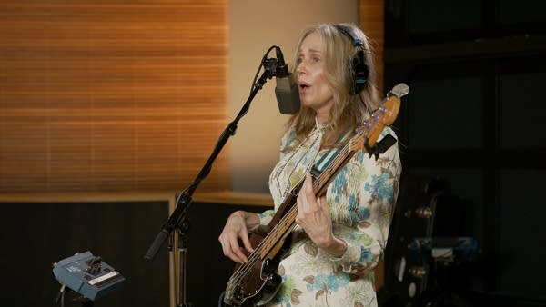 A musician sings and plays bass in a recording studio