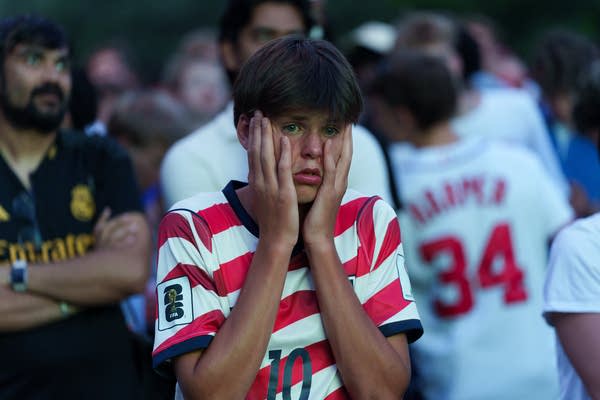 A fan holds their face