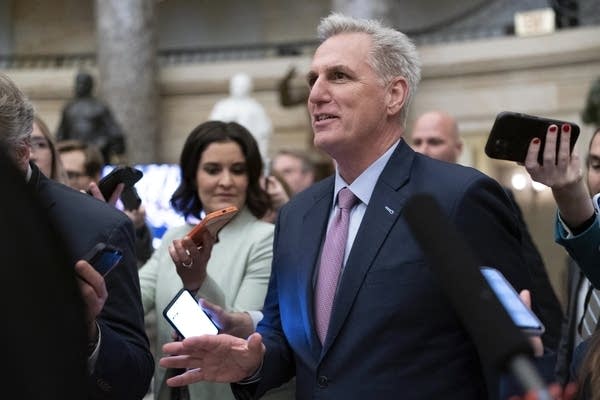 A man smiles and talks to reporters